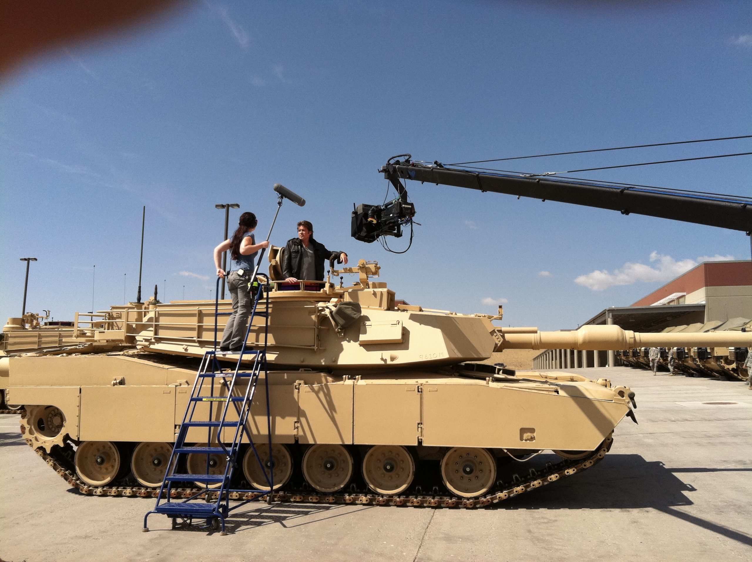Person resembling Billy Ray Cyrus standing in the turret of an M1A1 Abrams tank on a production location